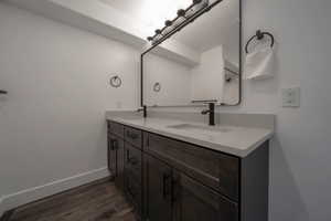 Bathroom with double vanity and dark wood-style floors
