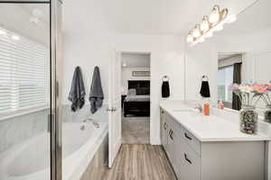 Ensuite bathroom featuring a bath, vanity, and light wood finished floors