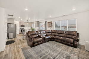 Living room with light wood-style flooring and recessed lighting