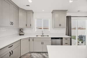 Kitchen featuring dishwasher, light stone counters, gray cabinets, decorative backsplash, and recessed lighting