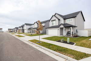 Modern farmhouse style home with a residential view, driveway, roof with shingles, covered porch, and a garage