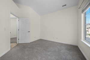 Empty room featuring light colored carpet and vaulted ceiling