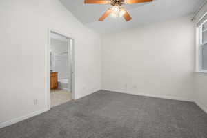 Unfurnished bedroom with light carpet, a ceiling fan, and connected bathroom