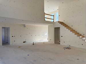 Unfurnished living room featuring a towering ceiling