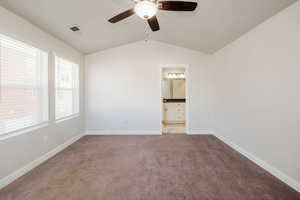 Unfurnished bedroom featuring vaulted ceiling, a ceiling fan, ensuite bath, and light colored carpet