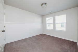 Carpeted empty room with a wainscoted wall