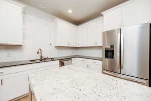 Kitchen with stainless steel appliances, dark stone countertops, decorative backsplash, white cabinetry, and recessed lighting