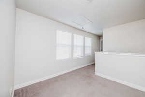Empty room with attic access and light carpet