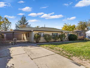 Ranch-style house featuring a front lawn, concrete driveway, and roof with shingles