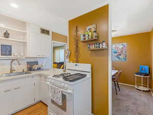 Kitchen featuring open shelves, white range with gas cooktop, white cabinetry, and recessed lighting