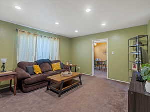 Living area with light carpet and recessed lighting