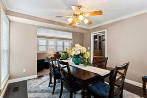 Dining space with ornamental molding, ceiling fan, and dark wood-style flooring