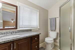 Full bath with a stall shower, vanity, ceiling fan, light tile patterned floors, and healthy amount of natural light