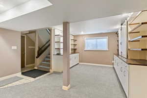 Below grade area with stairs, light carpet, a barn door, and recessed lighting