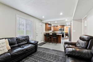 Living area with recessed lighting, a textured ceiling, and light tile patterned floors
