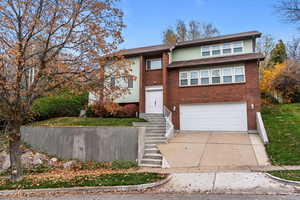View of front of house with driveway, a garage, and brick siding