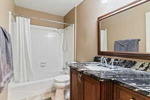 Full bathroom with vanity, shower / tub combo, and a textured ceiling