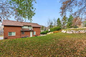 Rear view of property with a yard and brick siding