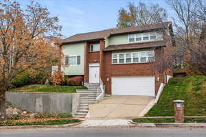 View of front of home featuring concrete driveway, a garage, brick siding, and a front yard