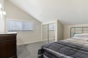 Carpeted bedroom featuring vaulted ceiling and a closet
