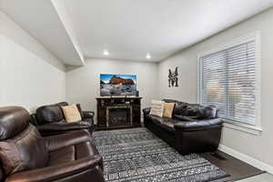 Living room with a glass covered fireplace, dark wood-style flooring, a textured ceiling, and recessed lighting