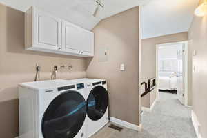 Laundry area with cabinet space, washer and clothes dryer, light carpet, lofted ceiling, and electric panel