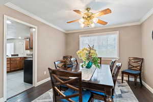 Dining room with dark wood-style flooring, ceiling fan, ornamental molding, and a textured ceiling