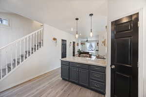 Kitchen featuring light stone countertops, a peninsula, light wood-style floors, pendant lighting, and open floor plan