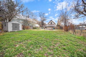Fenced backyard featuring a storage unit