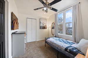 Carpeted bedroom featuring ceiling fan, a closet, and lofted ceiling