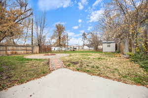 Fenced backyard featuring a storage shed