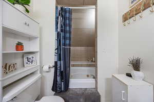 Full bath featuring toilet and a combined bath / shower with jetted tub