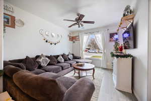 Living room with a ceiling fan and light wood-type flooring