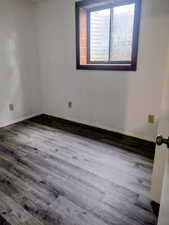 Empty room featuring baseboards and dark wood-style floors