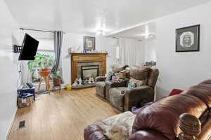 Living area with a textured ceiling, hardwood / wood-style floors, and a tiled fireplace