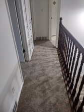 Hall with light colored carpet and an upstairs landing