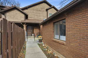View of exterior entry featuring brick siding and a shingled roof