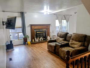 Living area with a textured ceiling, wood-type flooring, and a tile fireplace