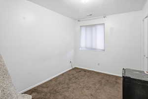 Carpeted spare room with a textured ceiling and baseboards