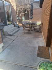 View of patio with outdoor dining space and entry steps