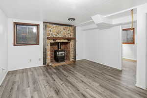 Unfurnished living room with a wood stove and wood finished floors