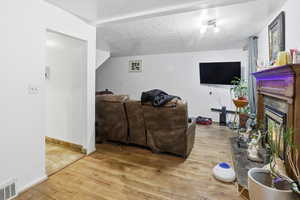 Living room with light wood-style flooring, a textured ceiling, and a high end fireplace