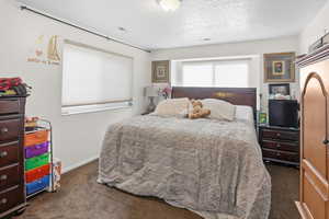 Bedroom with dark carpet and a textured ceiling
