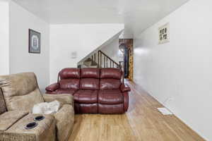 Living room featuring wood finished floors, a textured ceiling, and stairs