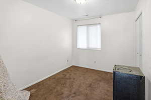 Unfurnished bedroom with dark carpet and a textured ceiling