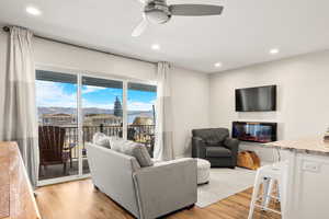 Living room with a glass covered fireplace, light wood-style floors, recessed lighting, and a ceiling fan