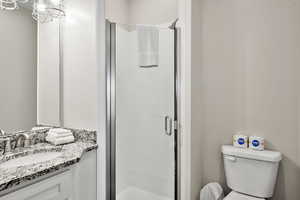 Bathroom featuring vanity, a stall shower, and a chandelier