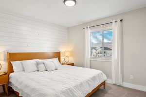 Bedroom featuring carpet floors and wood walls