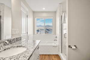Full bathroom featuring vanity, light wood-type flooring, a stall shower, and a garden tub
