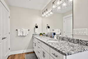 Full bath with double vanity, a chandelier, and dark wood finished floors